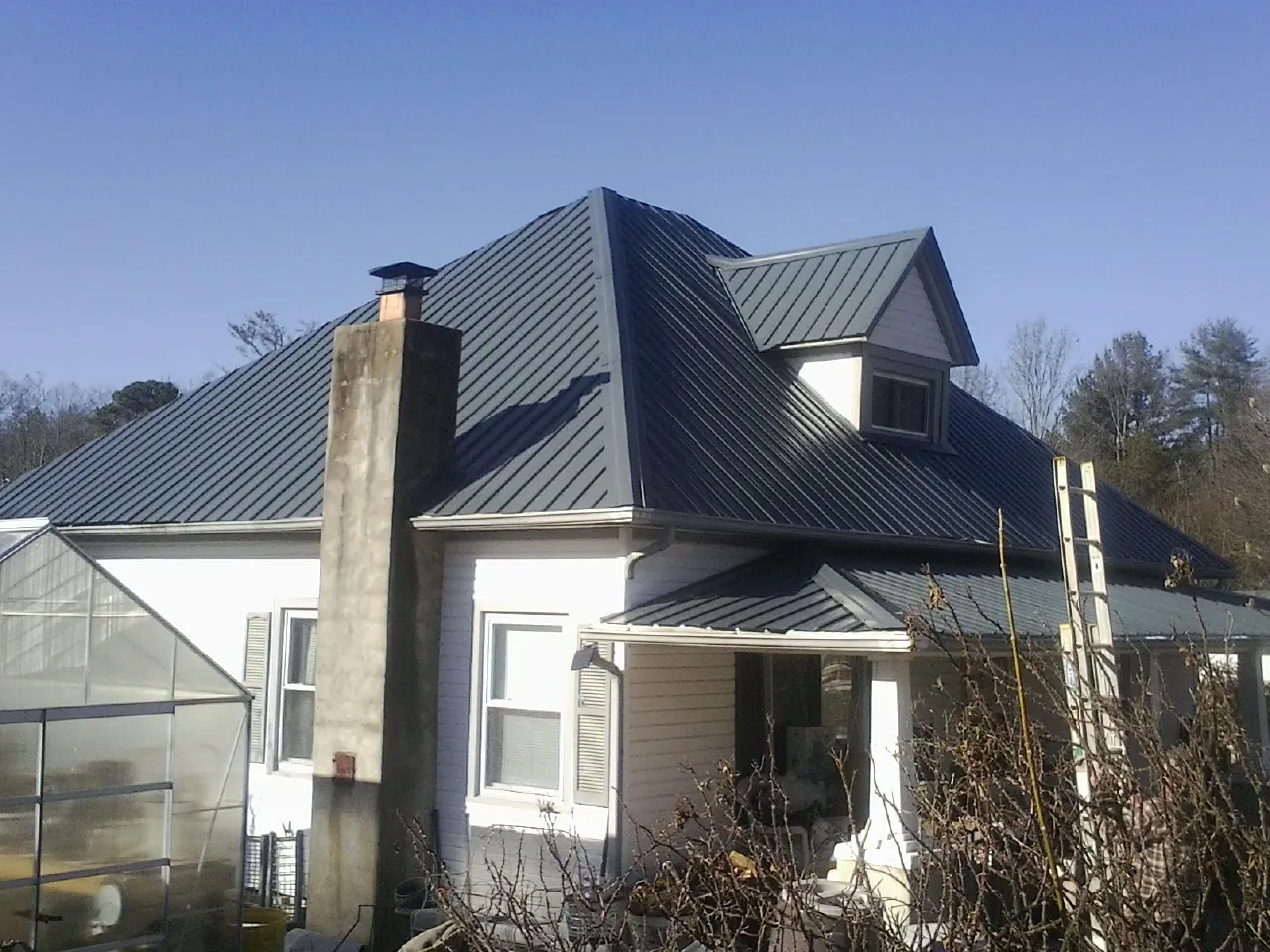 Dark blue standing seam metal roof on a white farmhouse with dormer — Slate & Tile Roof Repair by Roofing Brothers in Tujunga