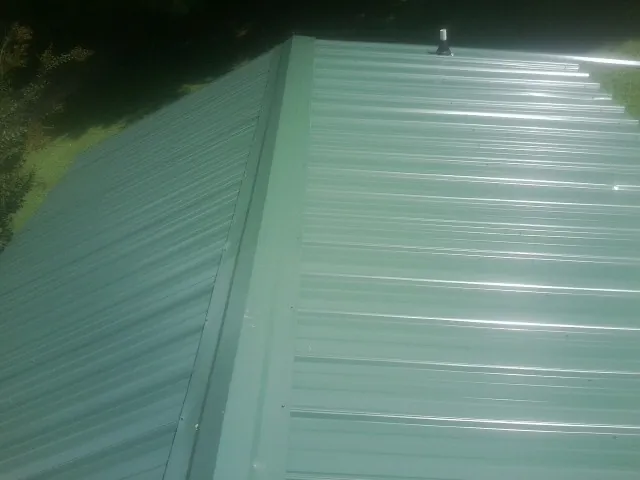 New green metal panels meeting at the ridge of a roof — Flat Roof Repair work by our crew in Tujunga